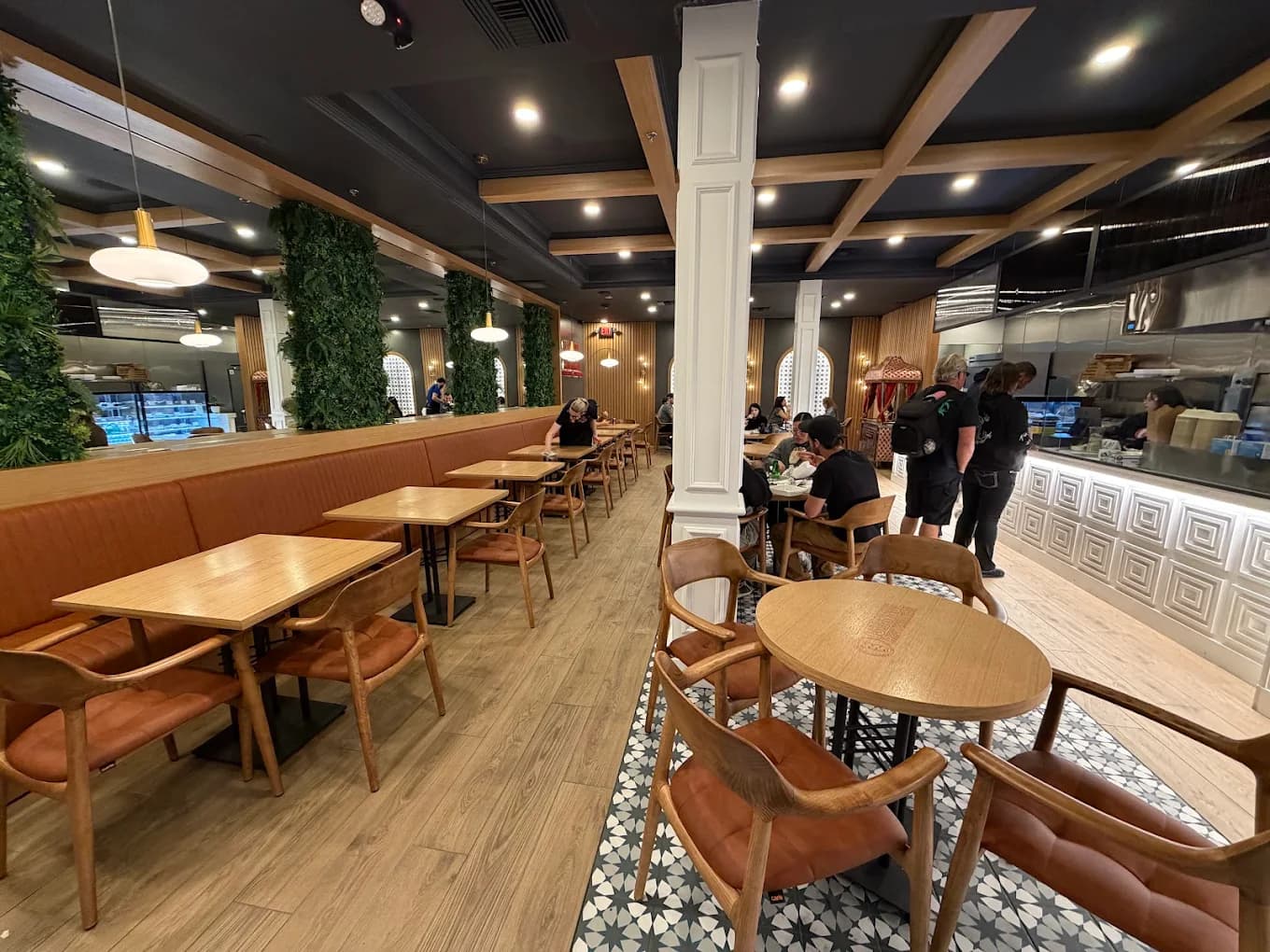 Busy dining room with living green walls, arched windows, and mosaic tile floors