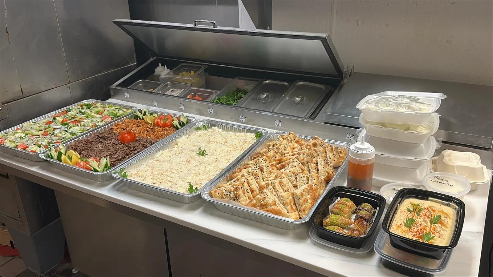 Full Halal catering spread prepared in the Istanbul Mediterranean 2 Fremont kitchen — fresh salad, doner, rice and pide trays