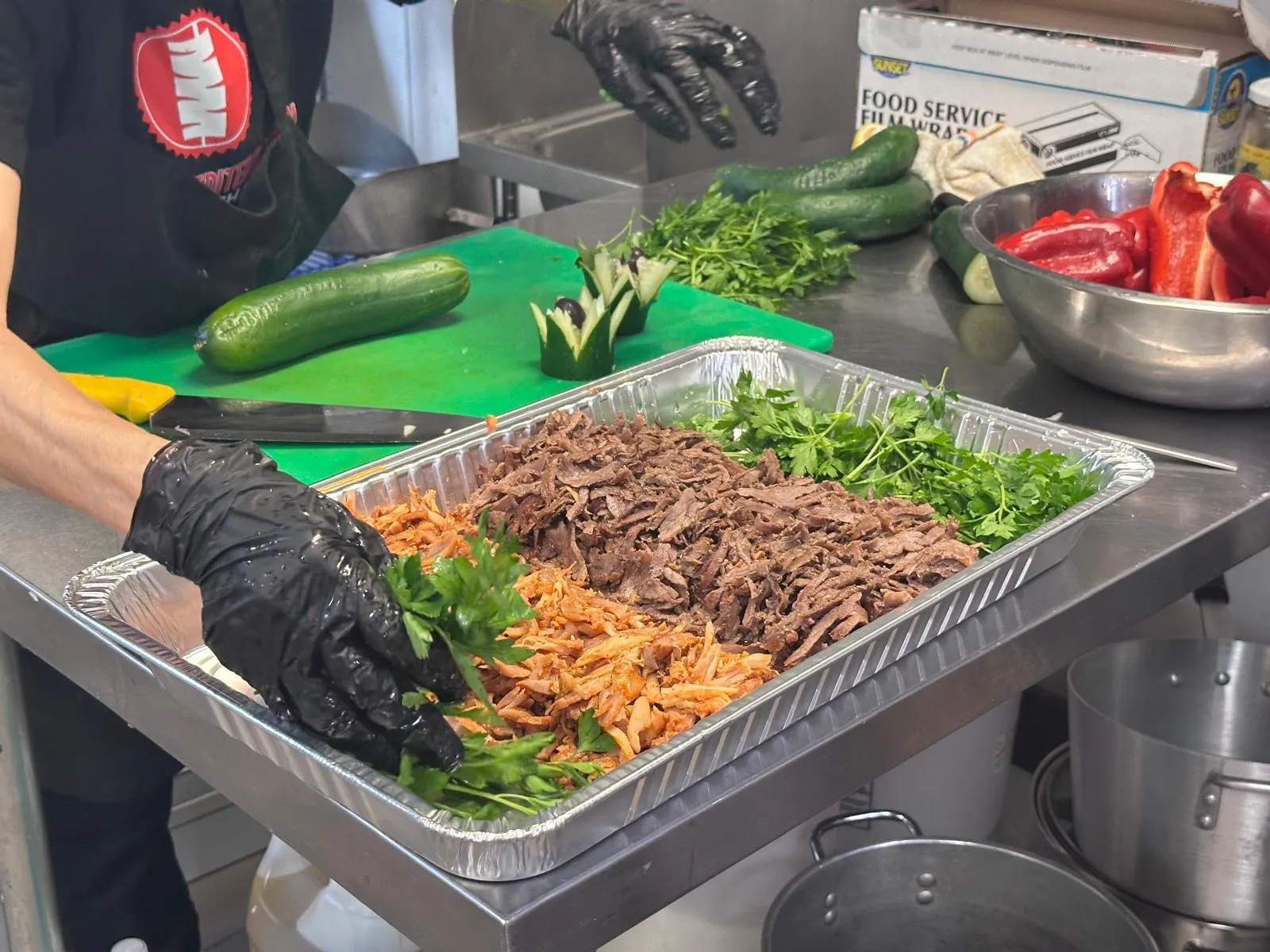 Chef garnishing a Halal doner catering tray with fresh parsley in the Istanbul Mediterranean 2 kitchen